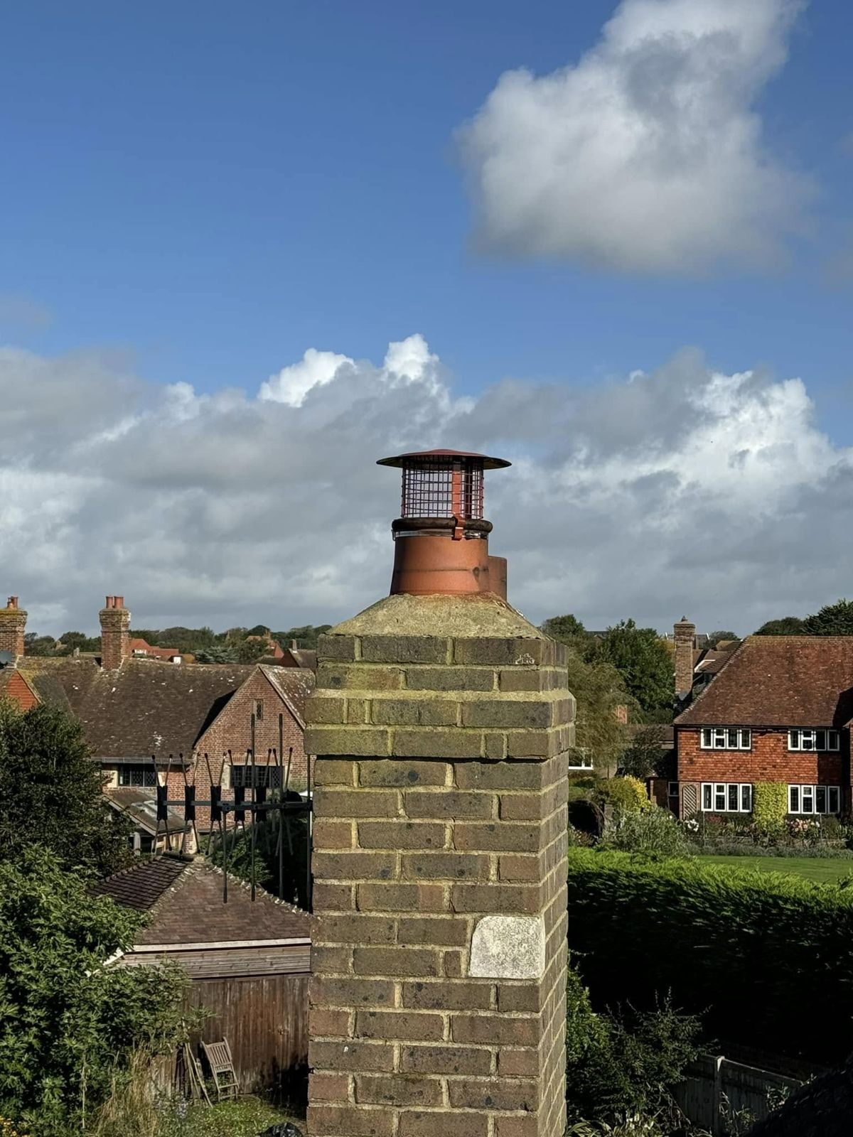 Cowl on a tall brick stack against a blue sky